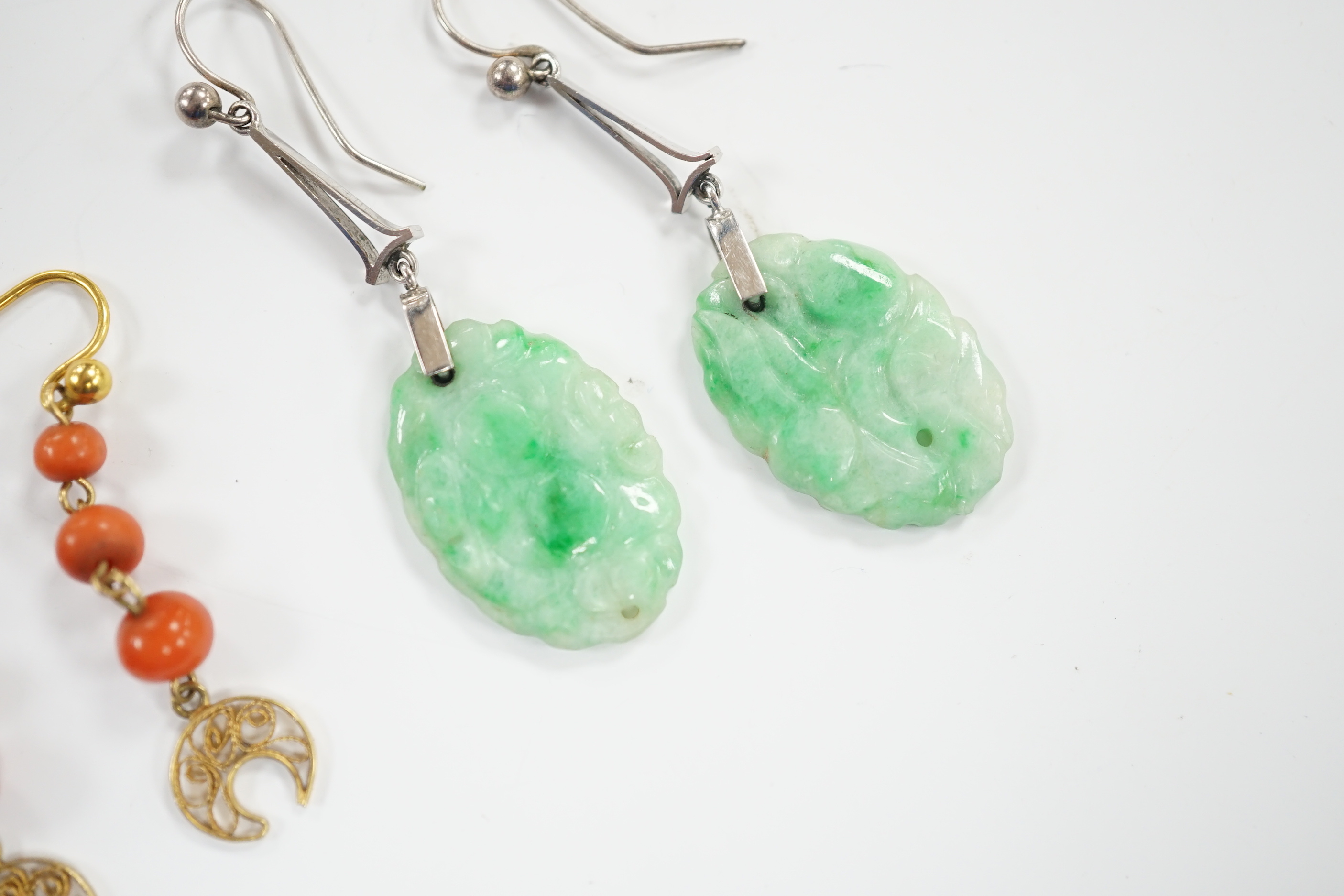 A pair of 9ct white metal and carved oval jade set drop earrings, jade 21mm and a pair of yellow metal and graduated three stone coral bead drop earrings, gross weight 6.2 grams.